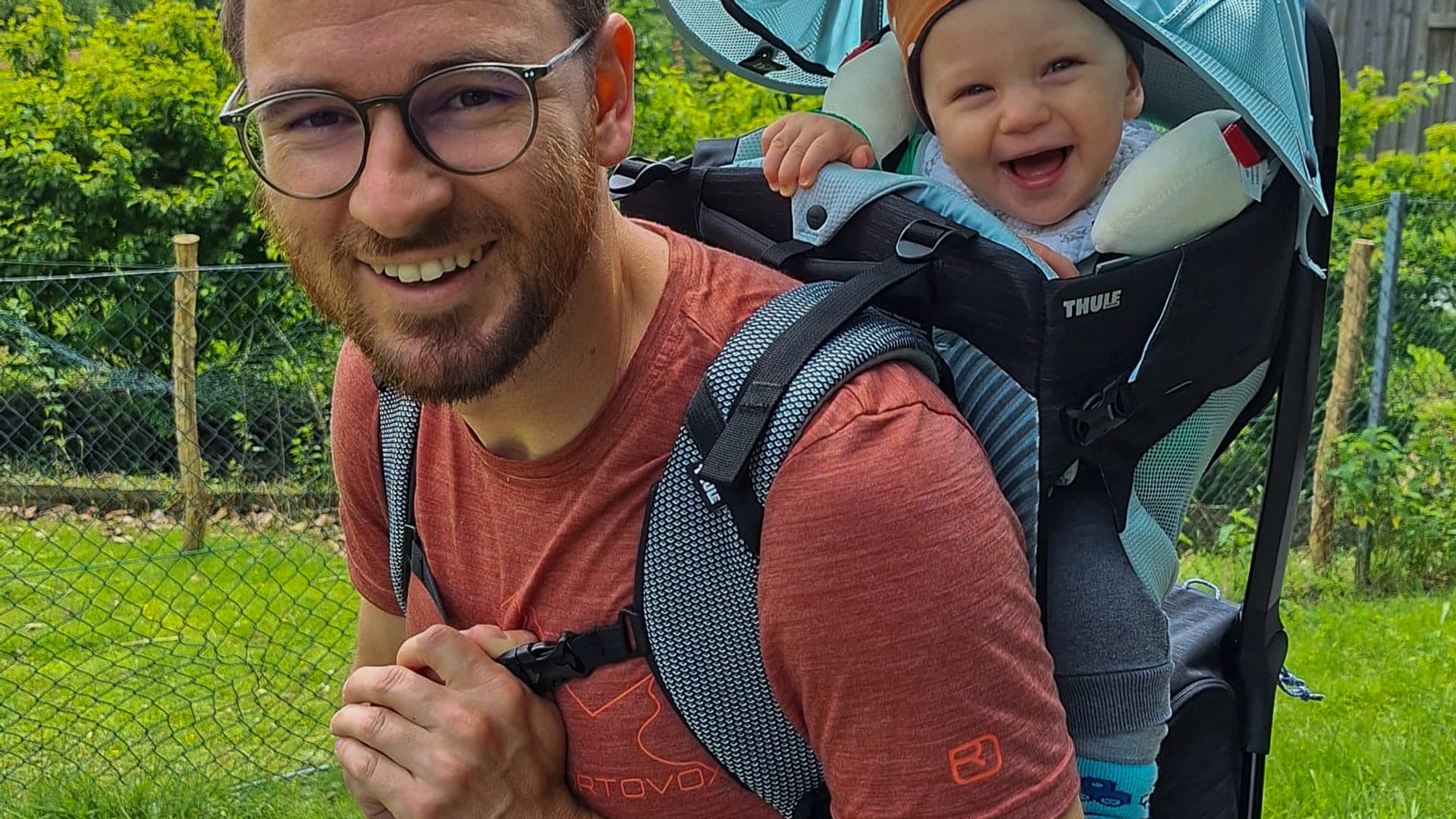 An employee with a baby in a back carrier in the garden